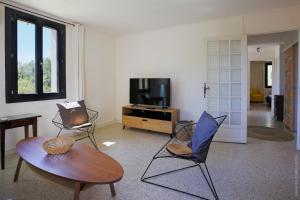 a living room with a table and chairs and a tv at Maison dans les Arbres, SPA, Tennis, Parking in Nîmes
