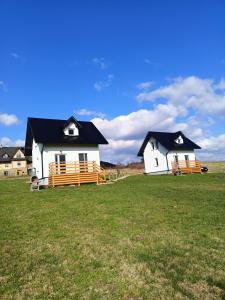 two white houses with black roofs in a field at Domki na Zapotocu in Grywałd