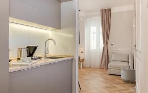 a kitchen with white cabinets and a sink and a chair at Luxury Rooms L'Avenue 2 Split in Split