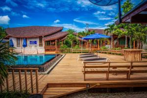 a wooden deck with chairs and a swimming pool at Tique Series Boutique Resort (SHA Extra Plus) in Ban Hat Lek