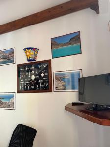 uma sala de estar com televisão e quadros na parede em Le case di Nunzia em Lampedusa