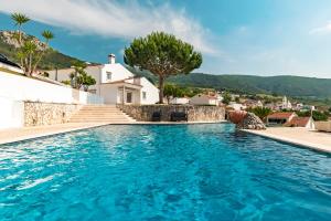 a swimming pool with a villa in the background at Casa da Eira in Cadaval
