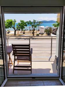 a bench sitting on a balcony looking out at the ocean at Sea View Apartments Nikos in Nea Peramos