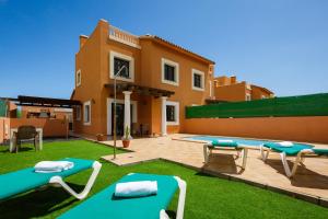 a villa with a swimming pool in front of a house at FTV Holidays Homes in Corralejo