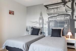 a bedroom with two beds with big ben in the background at voyageurs in Valognes