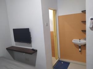 a bathroom with a sink and a tv on the wall at Rooms at Josapa Guest House in Batam Center