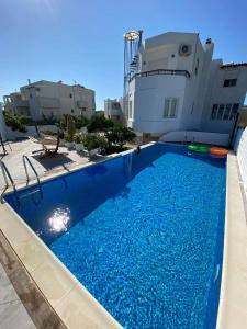 a large blue swimming pool in front of a building at Maria's little treasure in Pigianos Kampos
