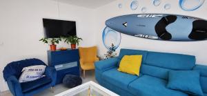 sala de estar con sofá azul y tabla de surf en la pared en Bulle Marine, en Calais
