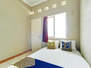Tempat tidur dalam kamar di SPOT ON 91135 Hanami Syariah