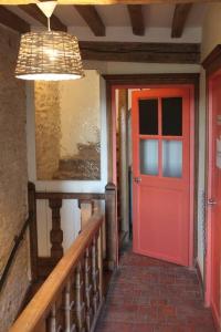 une porte rouge dans un couloir à côté d'un escalier dans l'établissement Cellier de l'abbaye- gîte Tête à Tête, à Vézelay