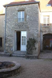 um antigo edifício de pedra com uma porta branca em Cellier de l'abbaye- gîte Tête à Tête em Vézelay