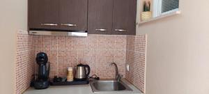 a kitchen with a sink and a tiled wall at Cactus Mini in Nydri