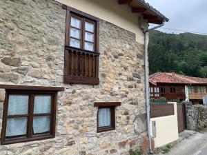 a stone building with three windows and a fence at La Nozaleda in Infiesto