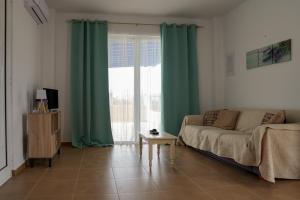 uma sala de estar com cortinas verdes e um sofá em Aelia House em Cidade de Kos