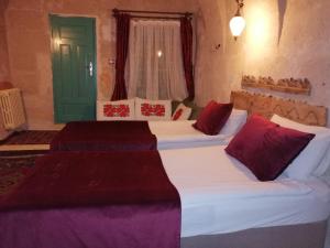 a bedroom with two beds with red pillows and a green door at patisca cave house in cappadocia in Urgup