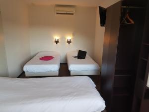 two beds in a small room with a laptop on it at Enzo Hotels Quimperle in Quimperlé