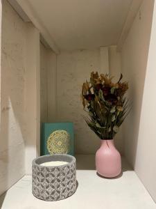 een roze vaas met een boeket bloemen en een doos bij Bel appartement chic et cosy. in Martres-de-Veyre