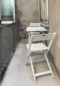 twee witte stoelen naast een tafel op een balkon bij Bel appartement chic et cosy. in Martres-de-Veyre