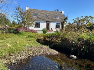 a house with a river in front of it at Taigh Iain Mhòir in Skeabost