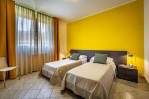 two beds in a hotel room with yellow walls at Casa Vacanze Arianna in Rosia +48 photos