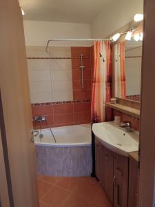 a bathroom with a bath tub and a sink at LARIX Apartman in Sárvár