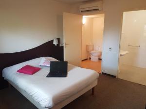 a bedroom with a bed with a laptop on it at Enzo Hotels Quimperle in Quimperlé