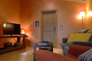 ein Wohnzimmer mit einem Sofa und einem TV in der Unterkunft Holiday home Ca' del Cinema in Mombercelli