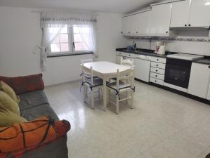 uma cozinha e sala de estar com uma mesa e um sofá em Apartamento Mar de Fóra em Finisterre