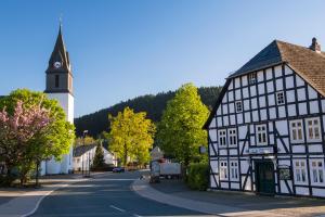 um edifício preto e branco com uma torre de relógio numa rua em TOP FeWo mit SommerCard em Winterberg