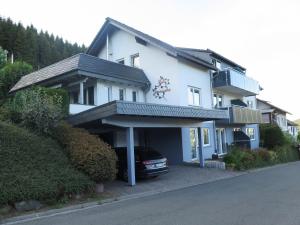 a white house with a car parked in the garage at Siebenglück - 4 FeWo's mit SommerCard in Winterberg
