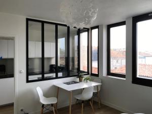 a dining room with a table and chairs and windows at Appartement Saint-Nicolas in La Rochelle