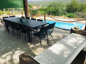 a black table and chairs next to a swimming pool at Villa Monte da Alfarrobeira in Estói