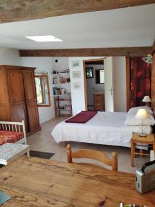 ein Schlafzimmer mit einem großen Bett in einem Zimmer mit einem Tisch in der Unterkunft Les Granges de la hulotte, les Mésanges in Lies