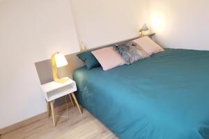 een slaapkamer met een blauw bed en een bijzettafel bij Joli duplex calme avec terrasse centre Paimpol in Paimpol