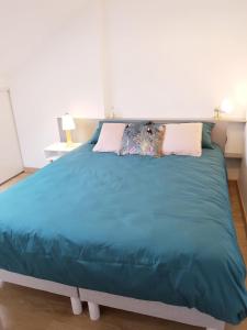 een groot bed met een blauw dekbed in een slaapkamer bij Joli duplex calme avec terrasse centre Paimpol in Paimpol