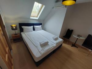 a bedroom with a bed with white sheets and a window at Palma Vendégház in Szeged