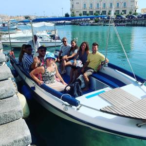 un grupo de personas sentadas en un barco en el agua en La Fonte Di Ortigia en Siracusa