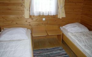 twee bedden in een kleine kamer met een raam bij Ferienhaus Nr 25, Typ A, Feriendorf Jägerpark, Bayerischer Wald in Viechtach