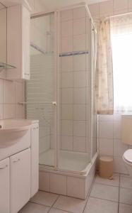 ein weißes Bad mit einer Dusche und einem Waschbecken in der Unterkunft Ferienhaus Nr 124, Typ A, Feriendorf Hochbergle, Allgäu in Karlsebene