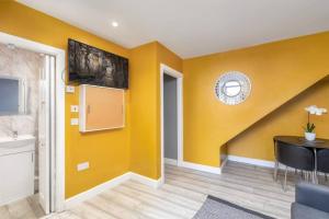 a room with yellow walls and a table and a clock at Luxury Living - Lovely 1 Bedroom Apartment in Stockton-on-Tees