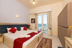 a bedroom with a large bed with red pillows at Fedra Hotel in Chrysi Ammoudia