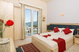 a bedroom with a large bed with red pillows at Fedra Hotel in Chrysi Ammoudia