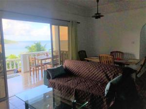 a living room with a couch and a view of the ocean at Seychelles Yellow Petals in Anse Boileau
