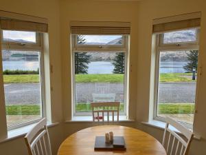 a table and chairs in a room with windows at Corran, Glenloch View, Fort William 2-Bedroom Loch Side Flat in Fort William