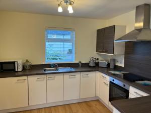 a kitchen with white cabinets and a sink and a window at Corran, Glenloch View, Fort William 2-Bedroom Loch Side Flat in Fort William