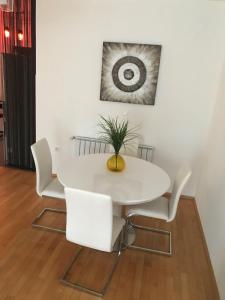 ein weißer Esstisch mit weißen Stühlen und einer Pflanze in der Unterkunft Apartment Angela with private garage slot in Pula