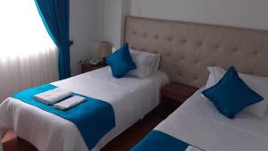 1 dormitorio con 2 camas y almohadas azules y blancas en Hotel en Bogota - Fontana Di Trevi, en Bogotá