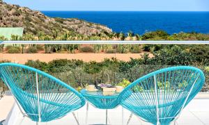 2 stoelen en een tafel op een balkon met uitzicht op de oceaan bij Cretan Lodge Heated Pool in Agios Nikolaos