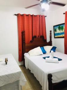 two beds in a room with red curtains at APARTAMENTOS IPAP LUPERON in Puerto de Luperon