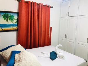 a bedroom with red curtains and an elephant on a bed at APARTAMENTOS IPAP LUPERON in Puerto de Luperon +18 photos